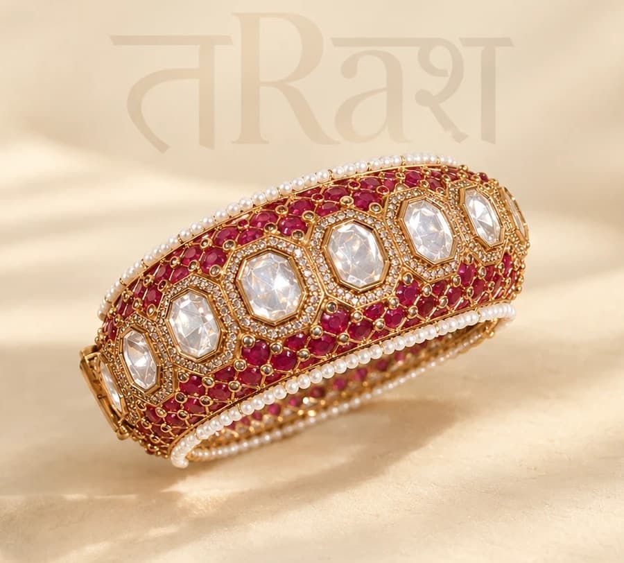 Manik — A broad hinged cuff set with a line of octagonal polki, each framed in white, on a ground of red and edged in seed pearls.